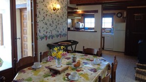 A dining area with a table set for two, a vase of flowers, and a kitchen in the background. - Cottage in Saint-Haon-le-Châtel with pool and pets allowed (Saint-Haon-le-Châtel)