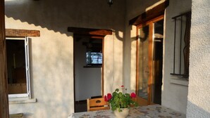 An outdoor patio with a table set for two, a potted plant, and a view of the interior. - Cottage in Saint-Haon-le-Châtel with pool and pets allowed (Saint-Haon-le-Châtel)