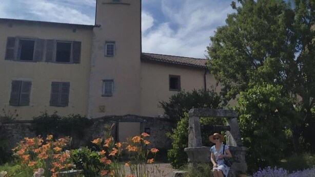 A building with a tower, a garden with flowers, and a person sitting on a bench. - Cottage in Saint-Haon-le-Châtel with pool and pets allowed (Saint-Haon-le-Châtel)