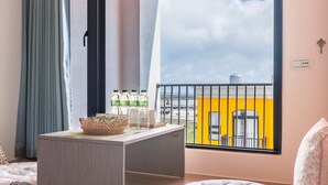 A hotel room with a large window, a balcony, a bed, a small table, and a chair. - Penghu Water Reflection (Magong)