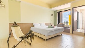 A modern hotel room with a large bed, a hammock, and a balcony with a view. - Penghu Water Reflection (Magong)