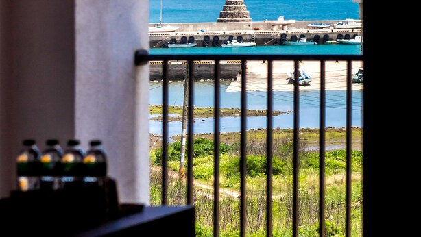 A balcony with a view of a coastal area, including a pier and boats. - Penghu Water Reflection (Magong)