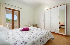Ein Schlafzimmer mit einem Bett, einem Kleiderschrank, einem kleinen Tisch und einem Sessel.
