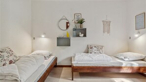 A bedroom with two beds, a wooden headboard, a wall-mounted shelf with decorative items, a macrame wall hanging, and a framed inspirational quote. - Stunning home in Nexø with WiFi (Nexø)