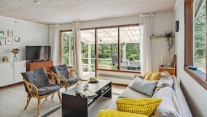 A spacious living room with a large window, a television, wicker furniture, and a cozy sofa. - Stunning home in Nexø with WiFi (Nexø)