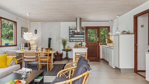 A modern living room with a sofa, dining table, and chairs. There is a kitchen area with cabinets and a refrigerator. - Stunning home in Nexø with WiFi (Nexø)