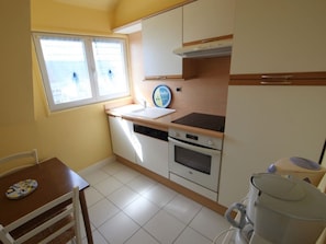 A compact kitchen with a window, a sink, a stove, and a dishwasher.