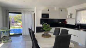 A modern kitchen with white cabinets, a black countertop, and a dining area with a white table and dark chairs. - Provencal detached villa (La Gaude)