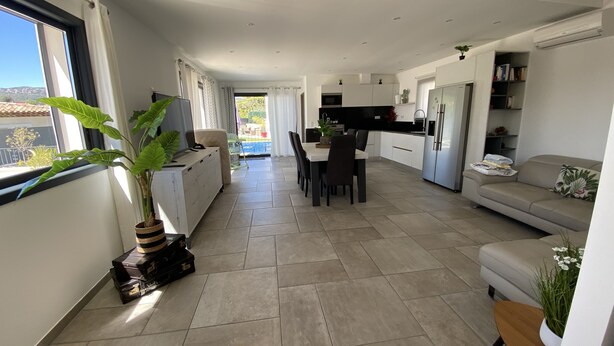 A modern kitchen with white cabinets, a dining area with a table and chairs, and a living area with a sofa and a TV. - Provencal detached villa (La Gaude)
