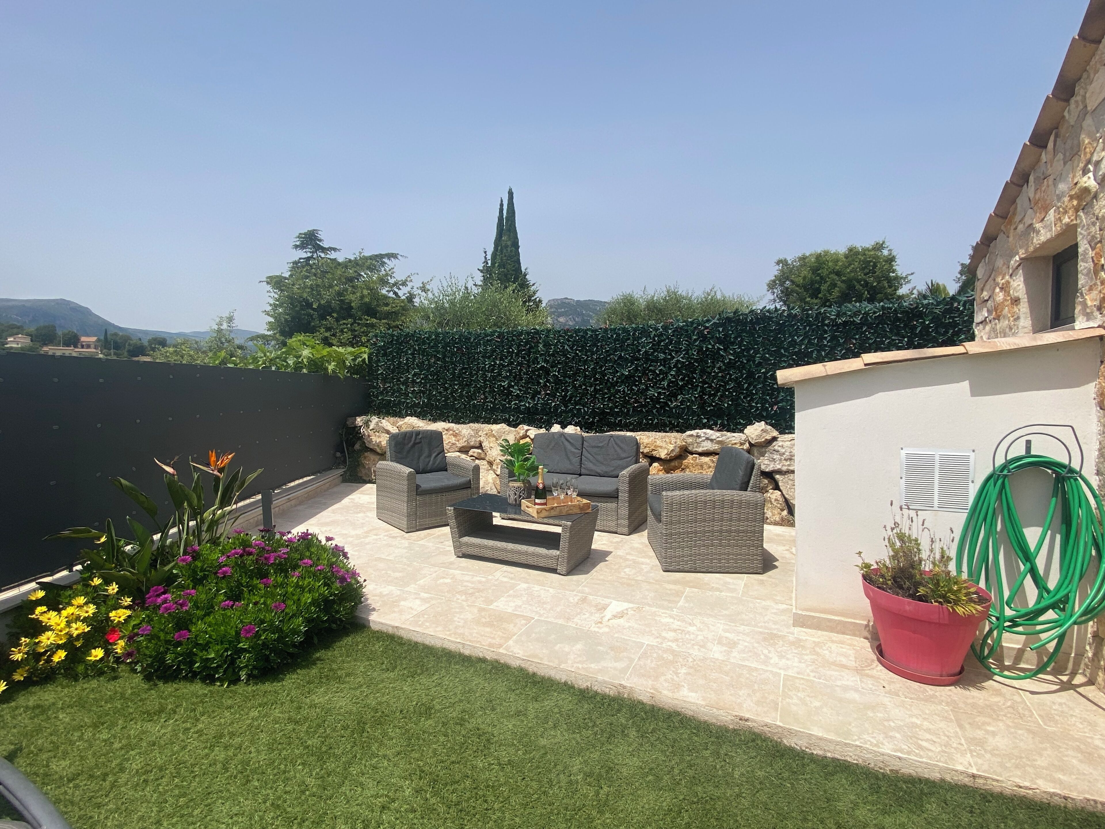 An outdoor patio with wicker furniture, a potted plant, and a view of distant hills and a church spire.
