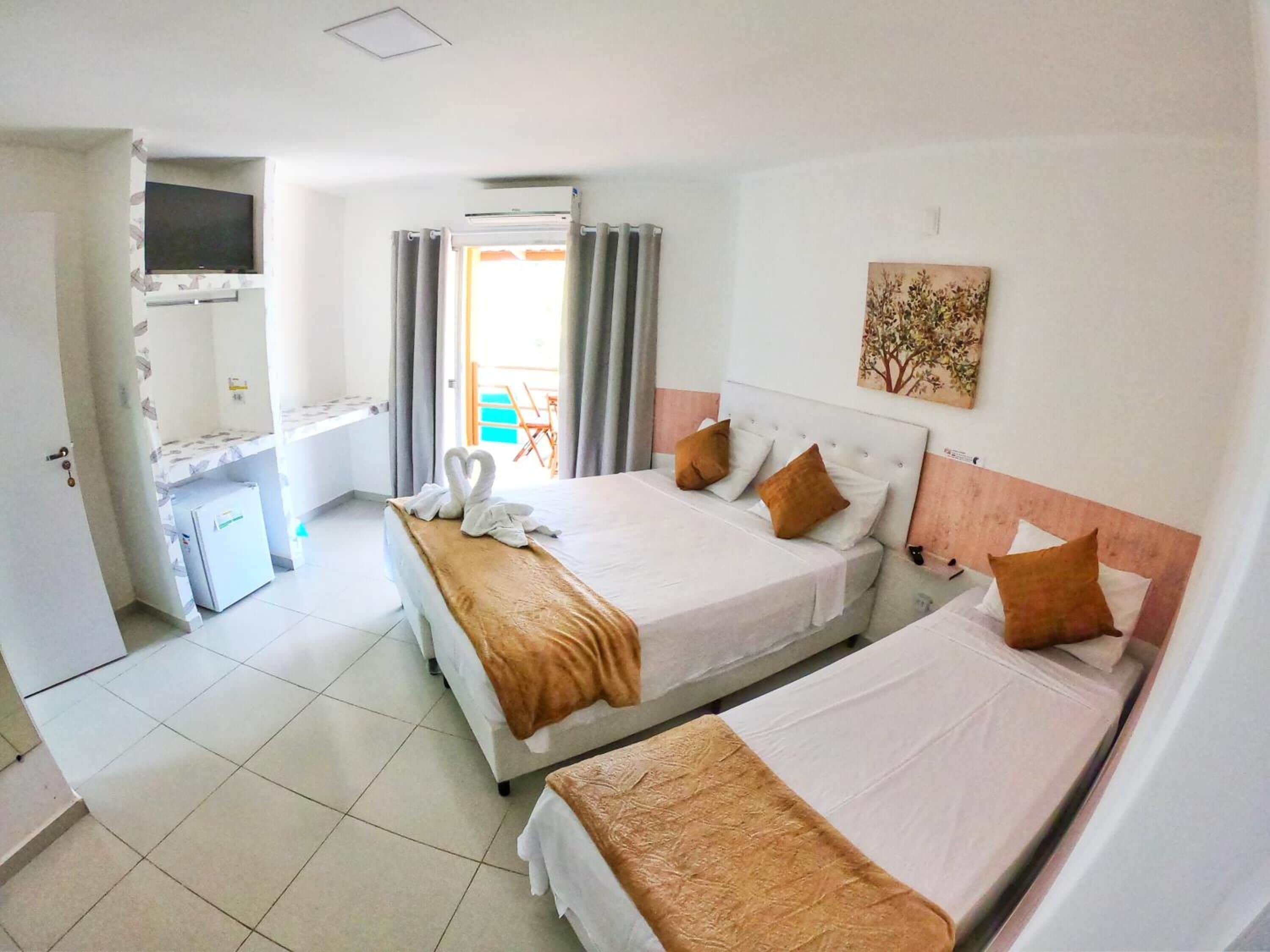 Une chambre d’hôtel avec deux lits, une télévision, un bureau et une vue sur l’extérieur.