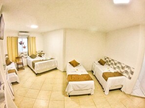 A hotel room with four single beds, a small table, and a chair. - Pousada Sereia do Porto (Ipojuca)