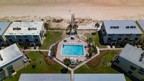 An aerial view of a resort with a central swimming pool, surrounded by multiple buildings with balconies. - August 2026 Big Savings!!! Remodeled bathrooms! BEACHFRONT (St. George Island)