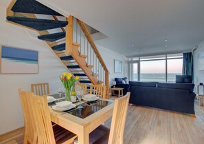 Contemporary living space with a dining area, sofa, and staircase leading to an upper level.