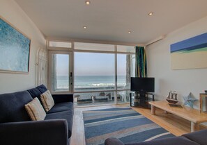Enjoy ocean views from the large window in this stylish living room, featuring a sofa, coffee table, and flat-screen TV.