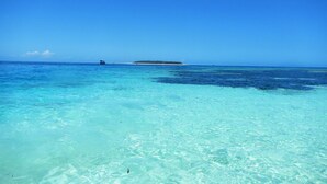 Un mar azul transparente con una pequeña isla a lo lejos.