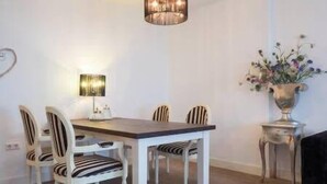 Et spiseområde med et træbord, stribede stole, en gulvlampe og en vase med blomster.