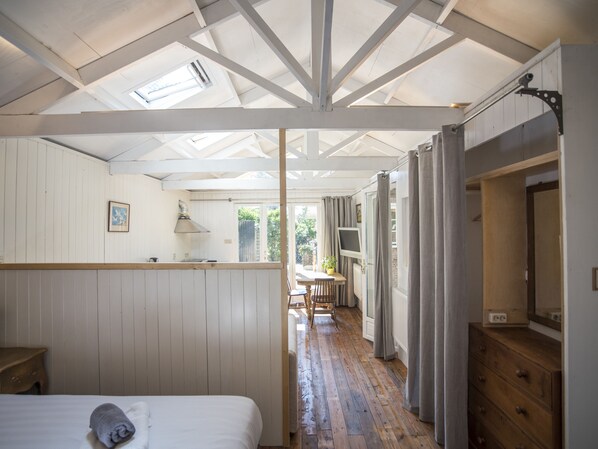 A room with a bed, a wooden desk, a chair, and a window with curtains.