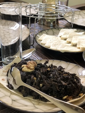 Taula de menjador amb un plat de menjar, un got d'aigua i una safata de metall.