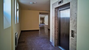 A hallway with a marble wall, an elevator, and a radiator. - Vanatun Monastery Stay (Dilijan)