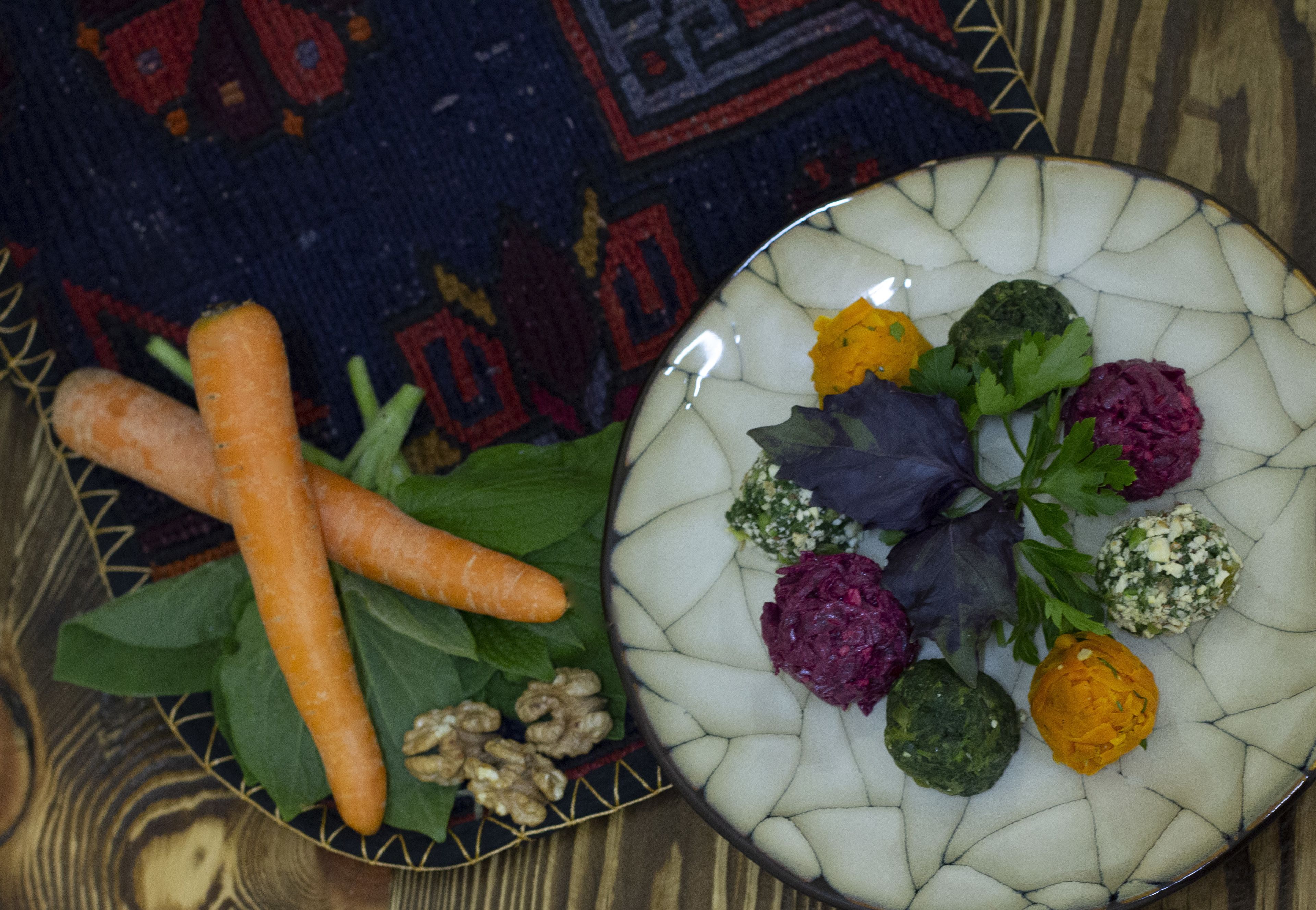 A plate with various vegetables and nuts on a table with a patterned rug in the background.