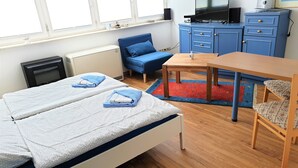 Une chambre avec deux lits, un bureau, une chaise, une télévision et une commode.