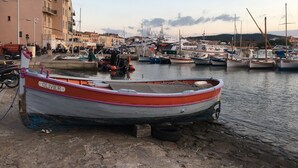 Un puerto con barcos amarrados, un edificio con balcones y un cielo despejado.