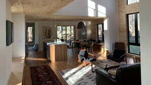 Un espacio habitable amplio con techo de madera, ventanas grandes y una isla central con lavamanos.