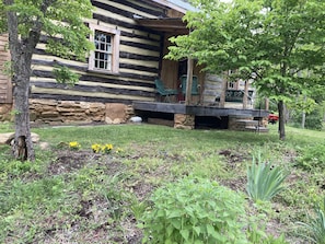 Step into this charming cabin, featuring a wooden deck with comfortable seating and a partially open door.