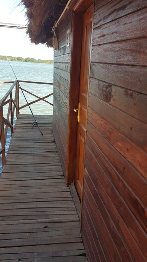 A wooden dock leading to a cabin with a door and a number sign. - Bintang Bolong Lodge (Kassagne)