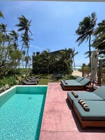 Zona de piscina con sillones de descanso y vista al océano.