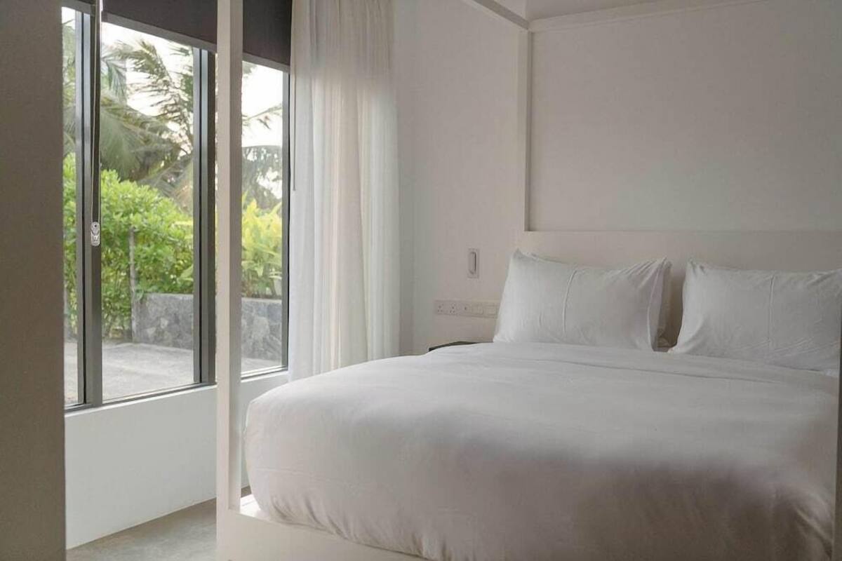 A bedroom with a large bed, a window, and a view of greenery outside.