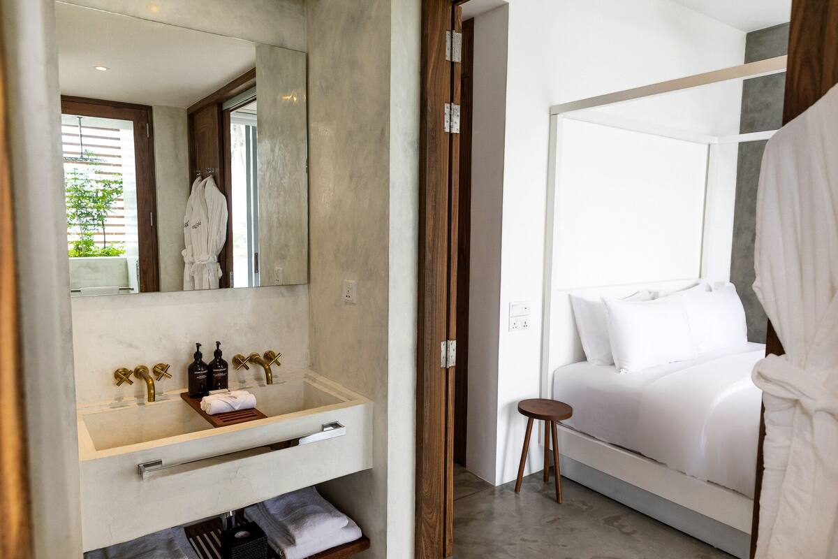 A modern bathroom with a large mirror, a wooden vanity, and a white bathtub.