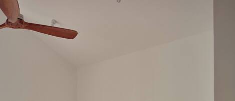 A hotel room with two beds, a ceiling fan, and a plain white wall.