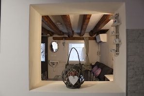 Um interior acolhedor com vigas de madeira expostas, um candeeiro em formato de coração e vista para uma sala de jantar.