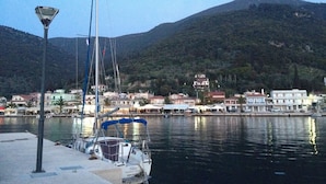 A marina with boats docked, a street lamp, and buildings in the background. - Steps from the Ionian Sea, literally 10m from barefoot bliss! (Karavomylos)