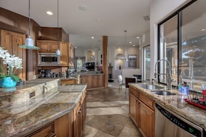 A modern kitchen with granite countertops, wooden cabinets, stainless steel appliances, and a large window providing natural light. - Luxury Resort Style Home -Spectacular Red Rock Views, Pool, Hot Tub, Firepit (Sedona)