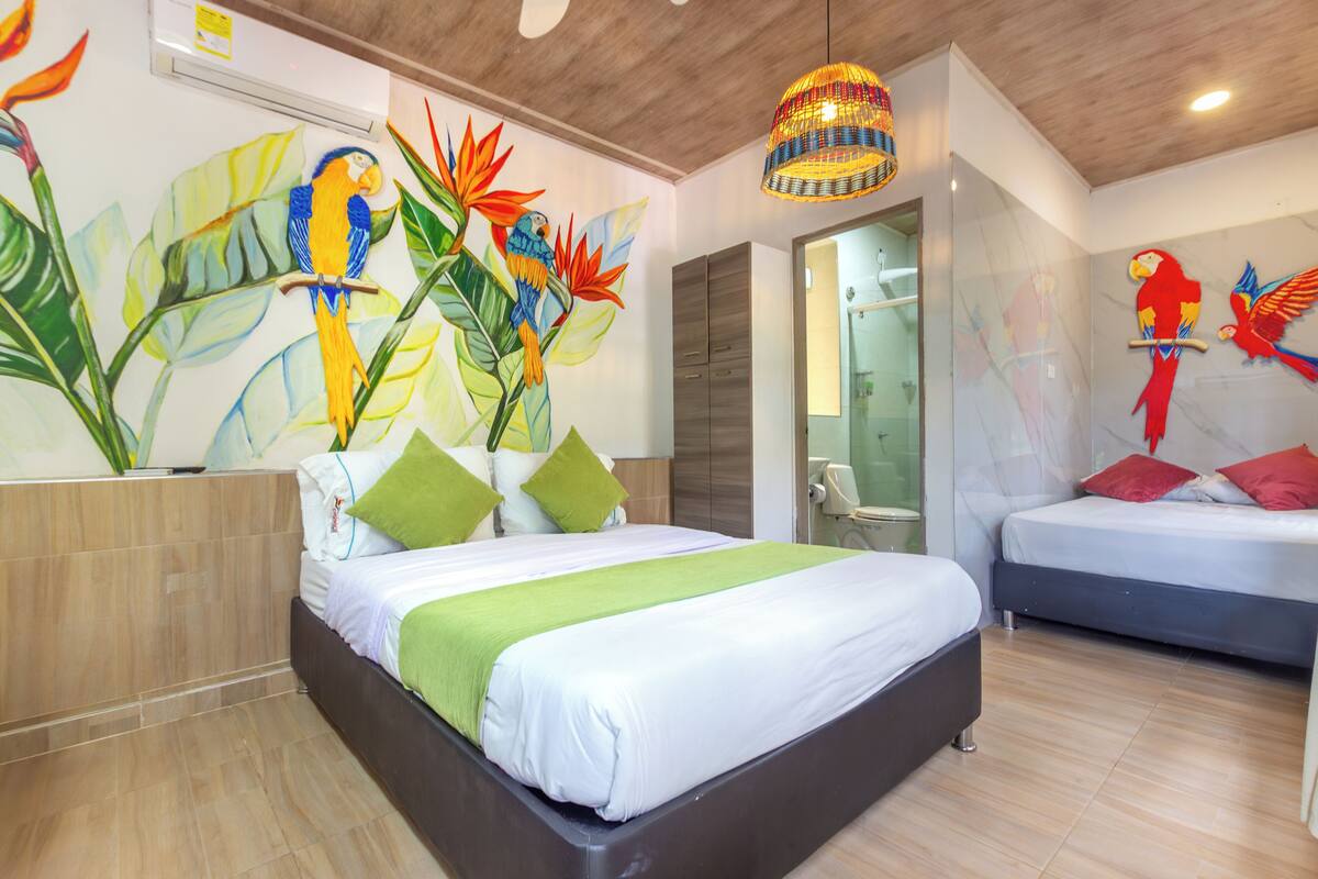 Un dormitorio moderno con una cama grande, una cama más pequeña y un baño visible a través de una puerta abierta.