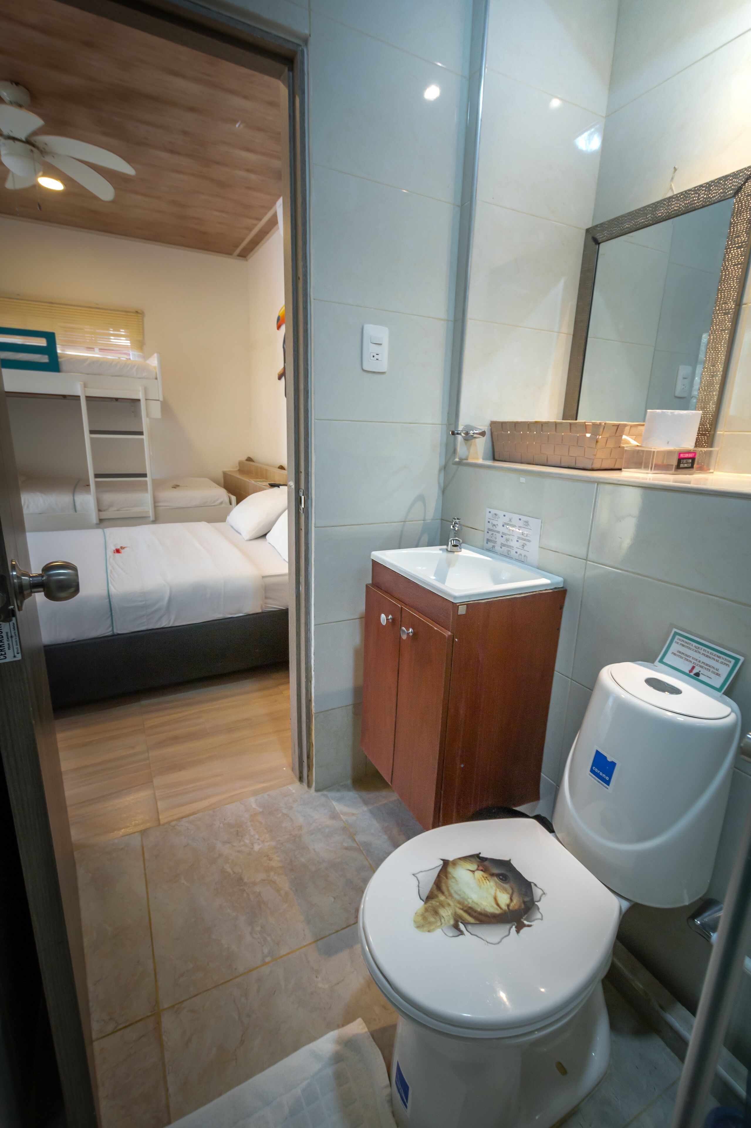 Habitación de hotel compacta con una cama individual, un baño pequeño con inodoro, lavabo y espejo.