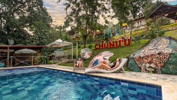 Ein Schwimmbecken mit zwei Liegestühlen und einem großen 'CHUNDU'-Schild im Hintergrund.