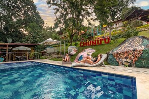Una piscina con dos sillas de descanso y un letrero grande que dice 'CHUNDU' al fondo.