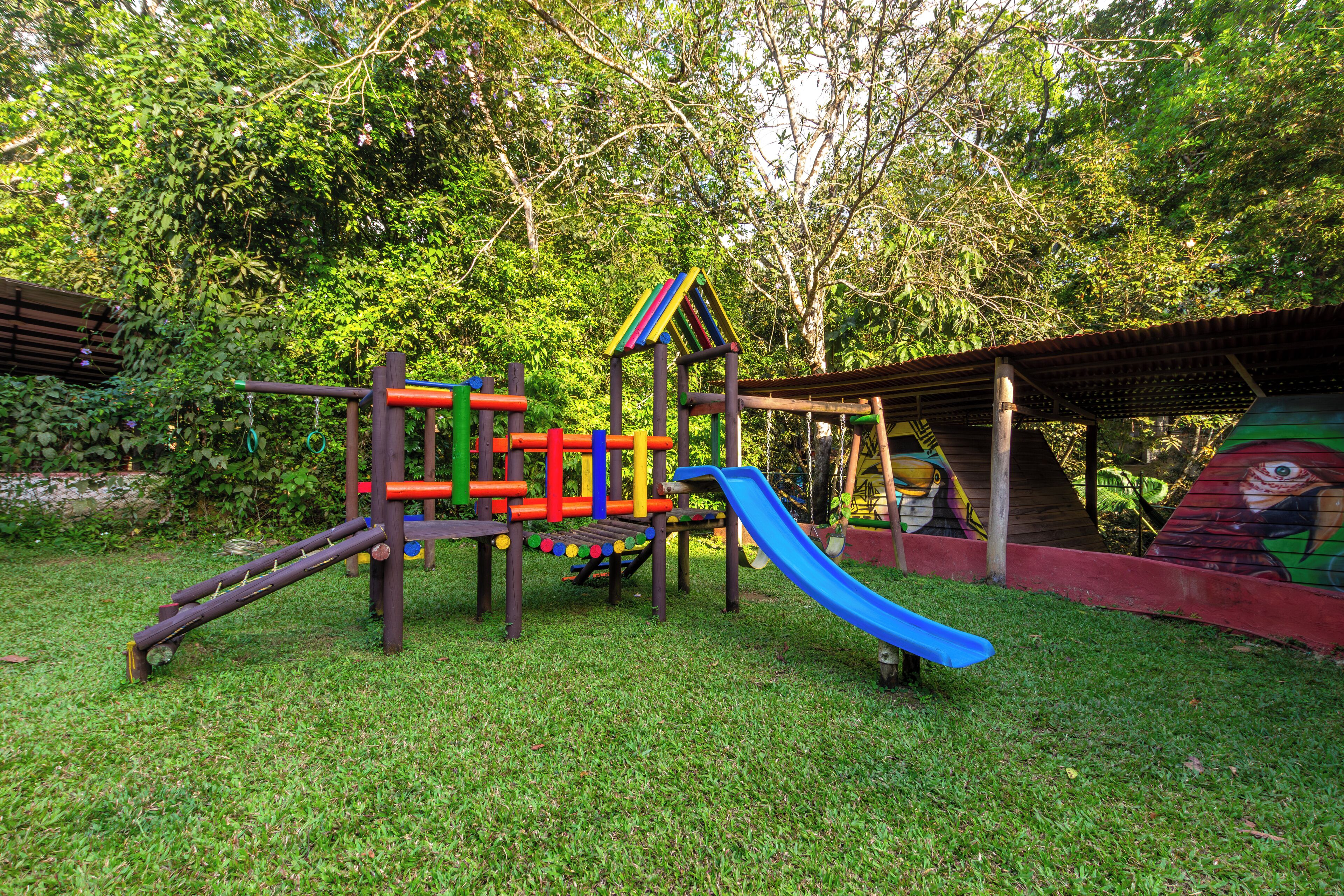 A playground with a slide, climbing structures, and a covered area with a mural.