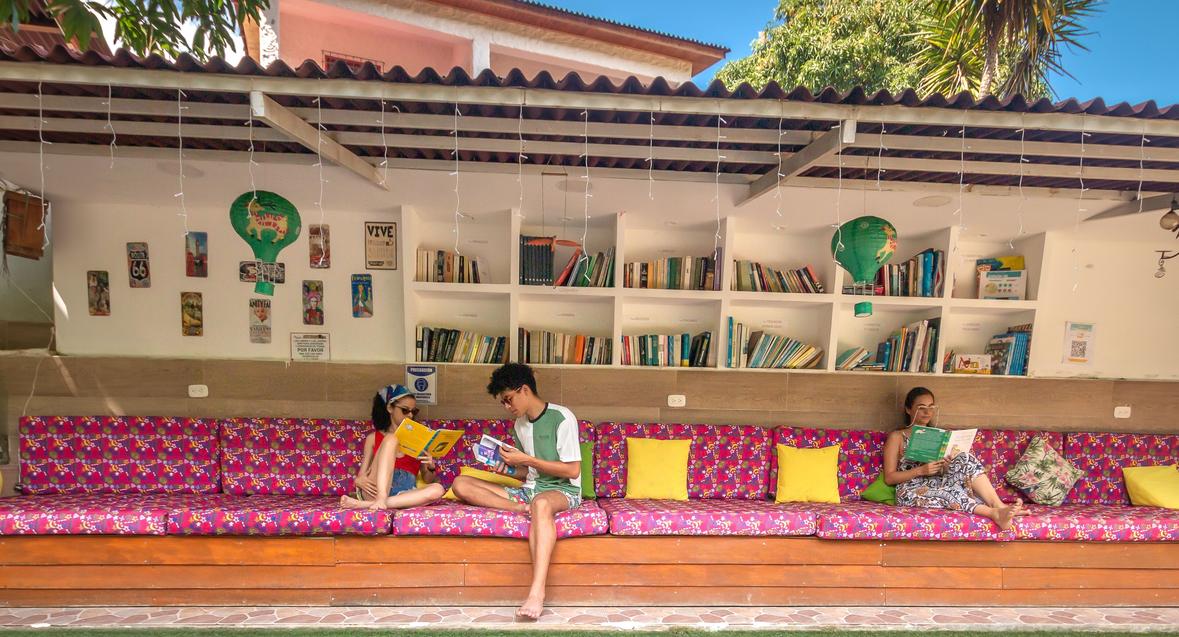 A covered outdoor seating area with a bookshelf and a sign indicating a smoking area.