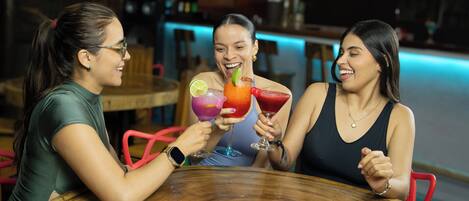 Three people sitting at a round wooden table in a bar setting.