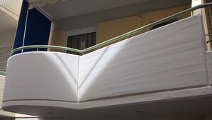 A corner of a building with a white balcony railing and a green handrail. - Orange Central Studio / Heraklion Crete  (Ηράκλειο)