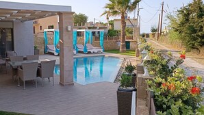 Un área de piscina con sillones de descanso y una pérgola.