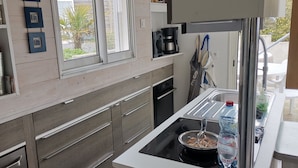 Una cocina moderna con estufa integrada, cafetera y ventana con vistas a la vegetación.