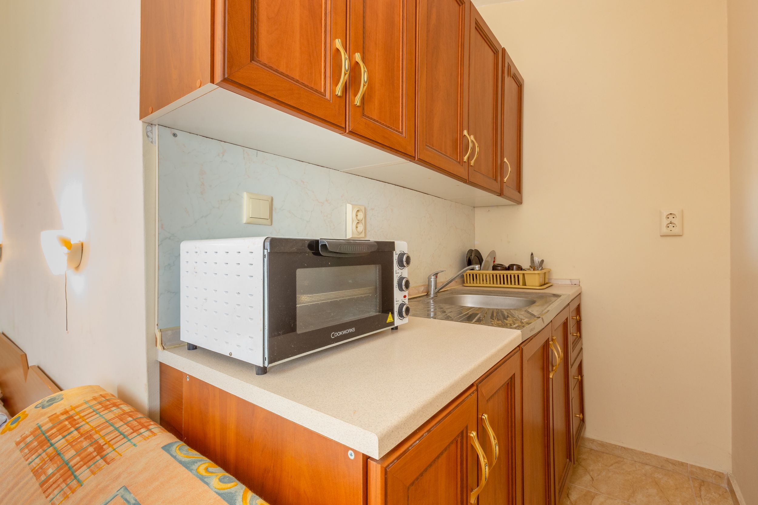 A compact kitchen with wooden cabinets, a built-in oven, and a countertop.