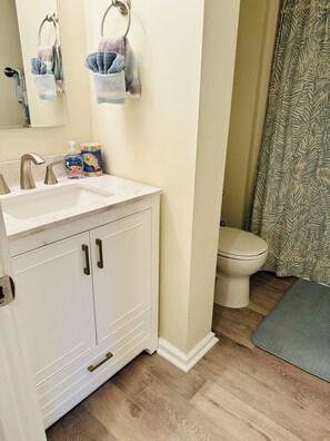 Een bad/douchecombinatie, een haardroger, handdoeken, zeep