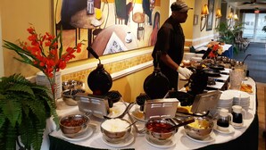 Ein reichhaltiges Buffet mit verschiedenen Speisen und einer Person, die etwas serviert.
